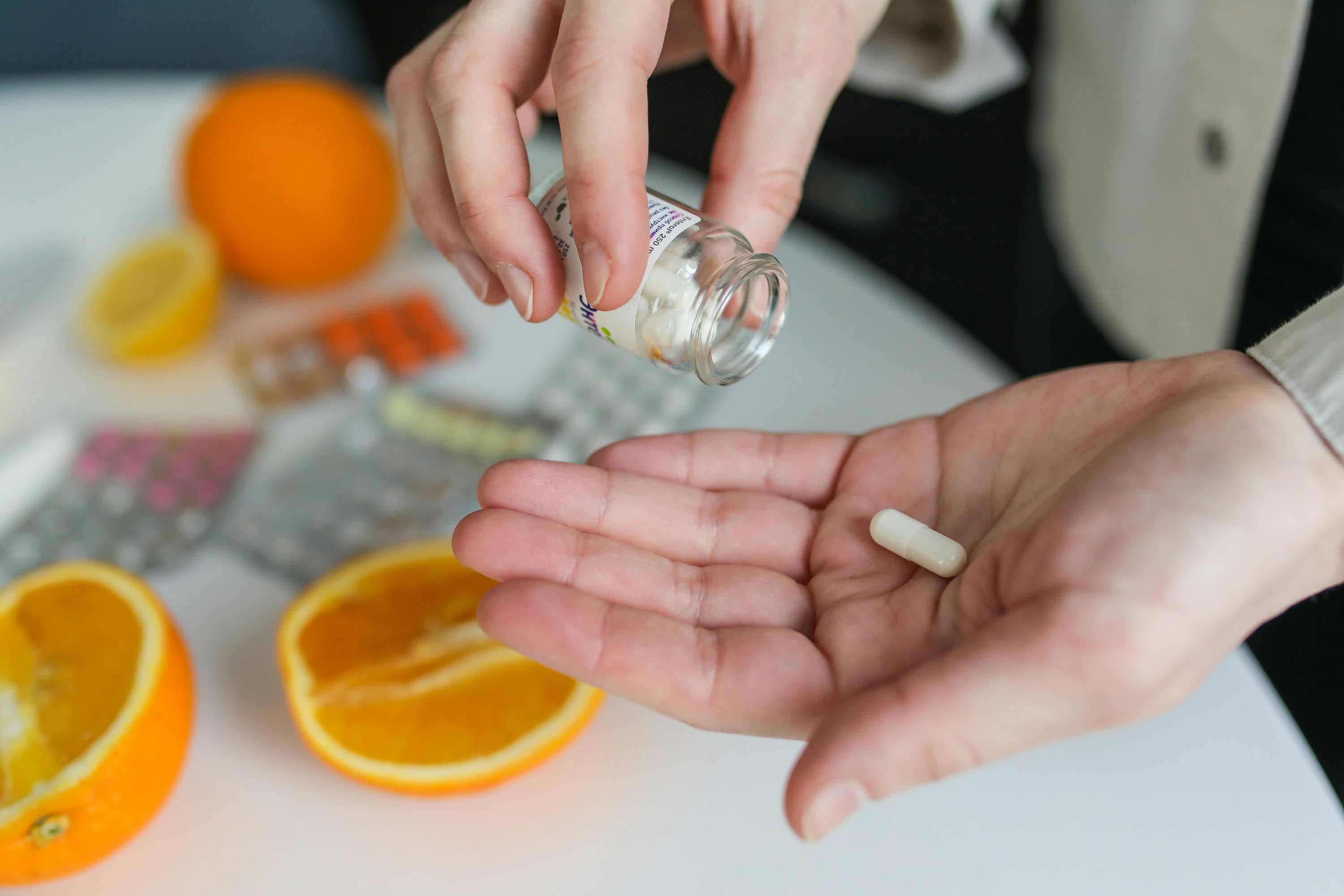 Hands holding dietary supplements and vitamins with citrus fruits